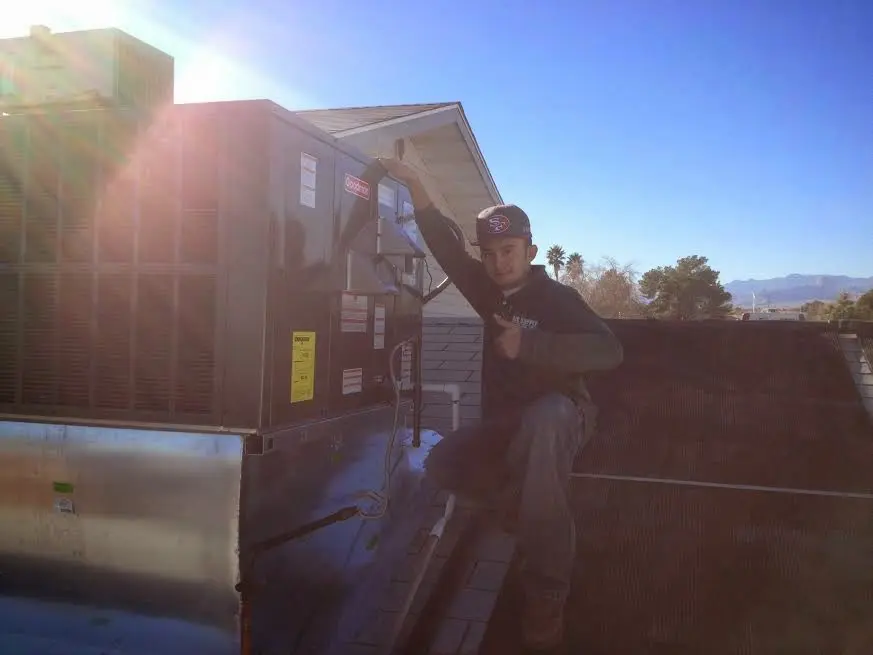HVAC technician performing Air Duct Cleaning on a rooftop unit in Montague